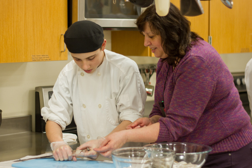 Kimberly Miller helps a Culinary Arts student prepare a squid for an upcoming calamari dish. Kimberly Miller helps a Culinary Arts student prepare a squid for an upcoming calamari dish.